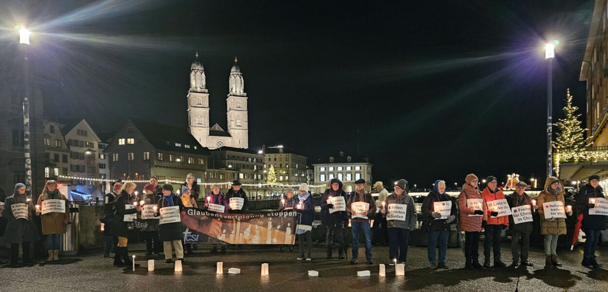 Persone riunite con candele e cartelloni per la Veglia CSI a Zurigo. csi