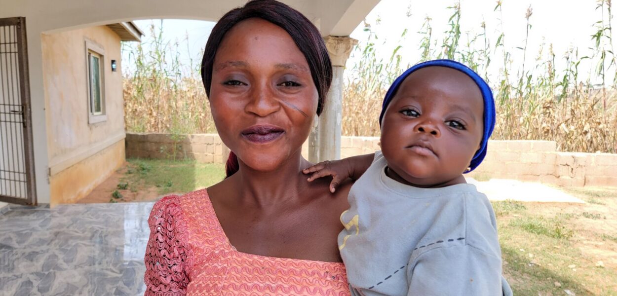 Primo piano di donna nigeriana sorridente con in braccio il suo bebé. csi
