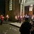 Persone riunite in preghiera silenziosa con dei lumini davanti a una chiesa.