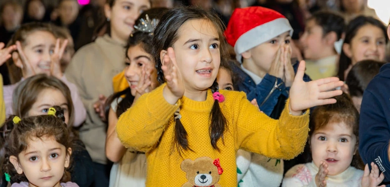 Bambini armeni cantano e battono le mani a una festa di Natale. csi
