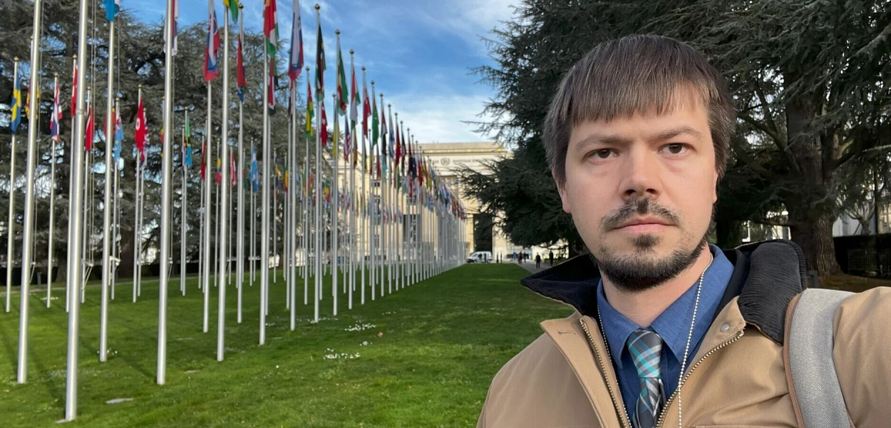 Primo piano di Joel Veldkamp (CSI) e della fila di bandiere delle nazioni davanti alla sede dell'ONU a Ginevra.